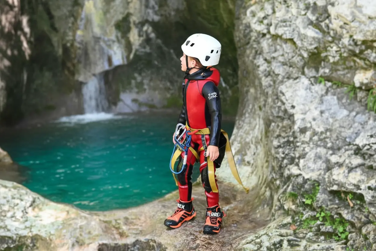 Child standing by turquoise pool during canyoning adventure in Bled Slovenia